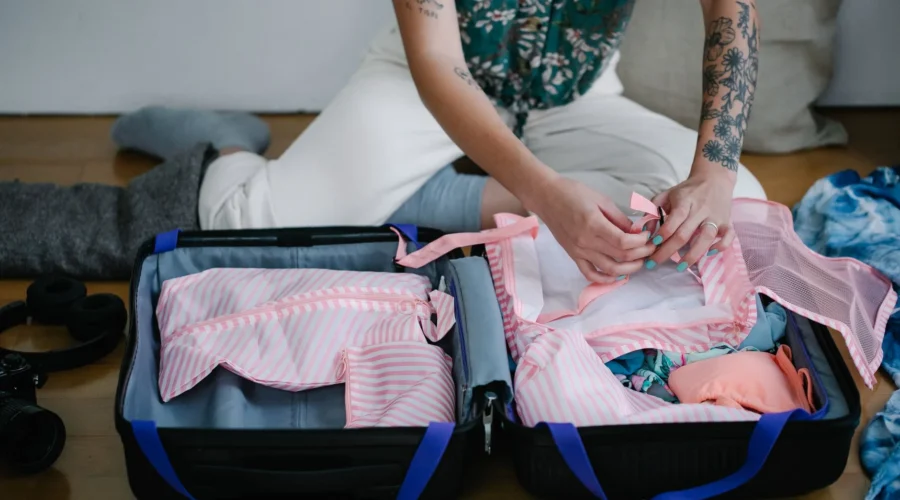 Ilustrasi cara packing untuk liburan panjang dengan melipat baju secara rapi di dalam koper