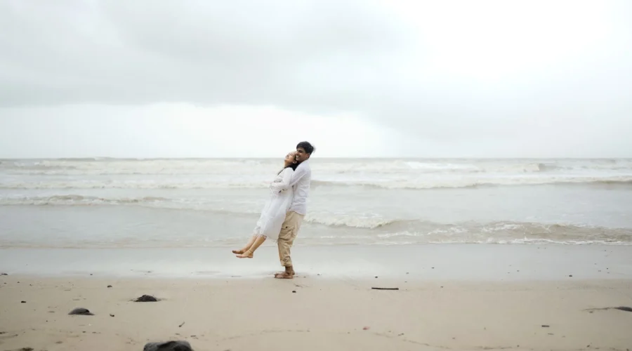 Pasangan sedang menikmati liburan romantis di pantai saat matahari terbenam
