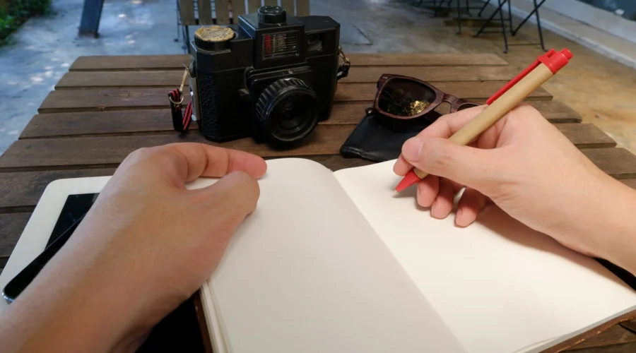 Seseorang menulis jurnal di meja kerja yang rapi sebagai tips hidup lebih tenang