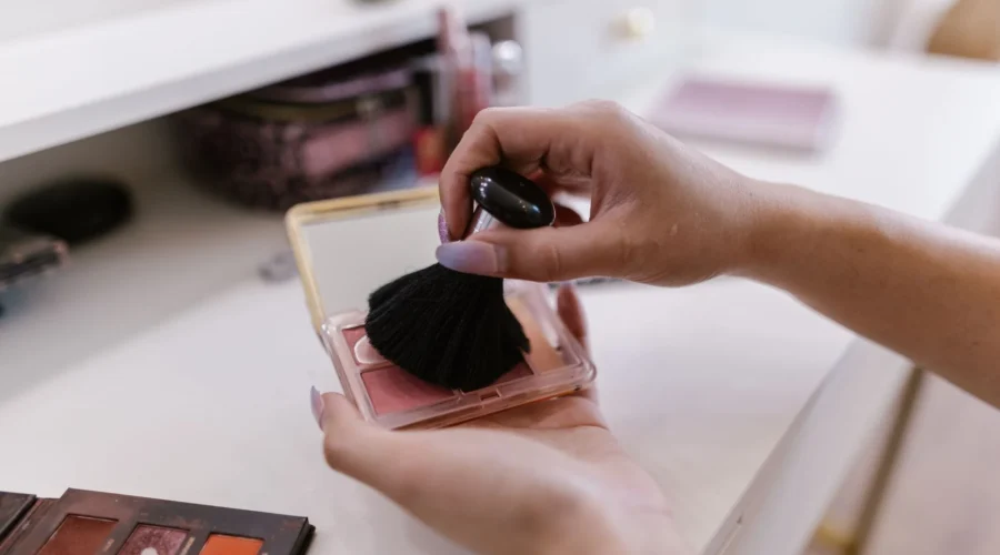 Wanita mengoleskan blush on natural pada pipi dengan warna peach lembut